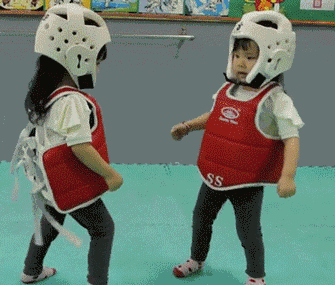 Two children in sparring gear gently fighting